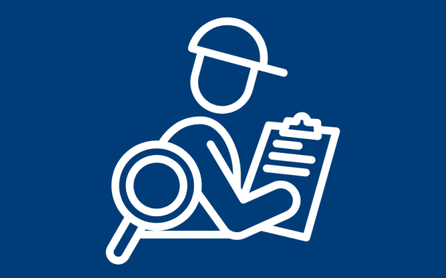 Person wearing a hardhat, looking at a form with a magnifying glass