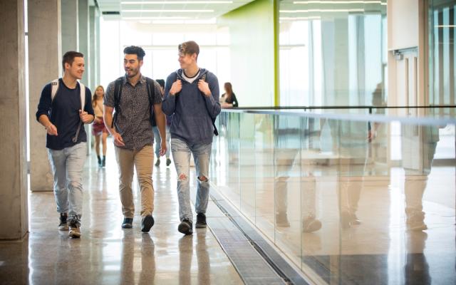 Three male students walking in Science Commons