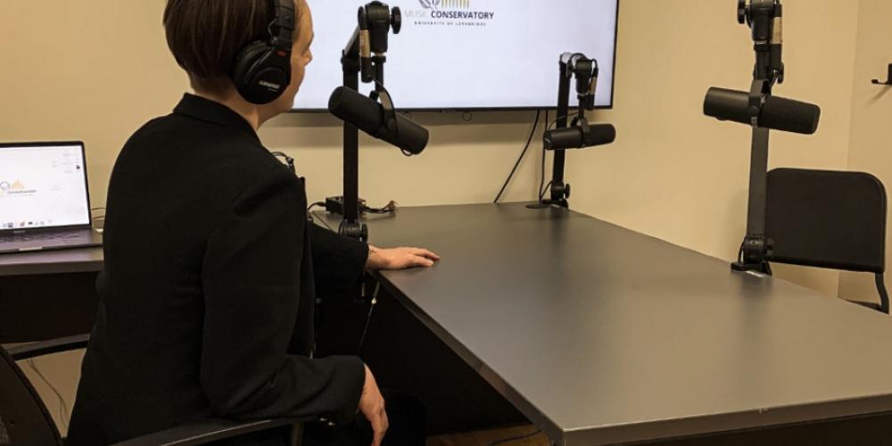 person sitting with headphones on in front of mic