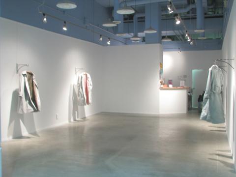 art installation with lab coats hanging from walls